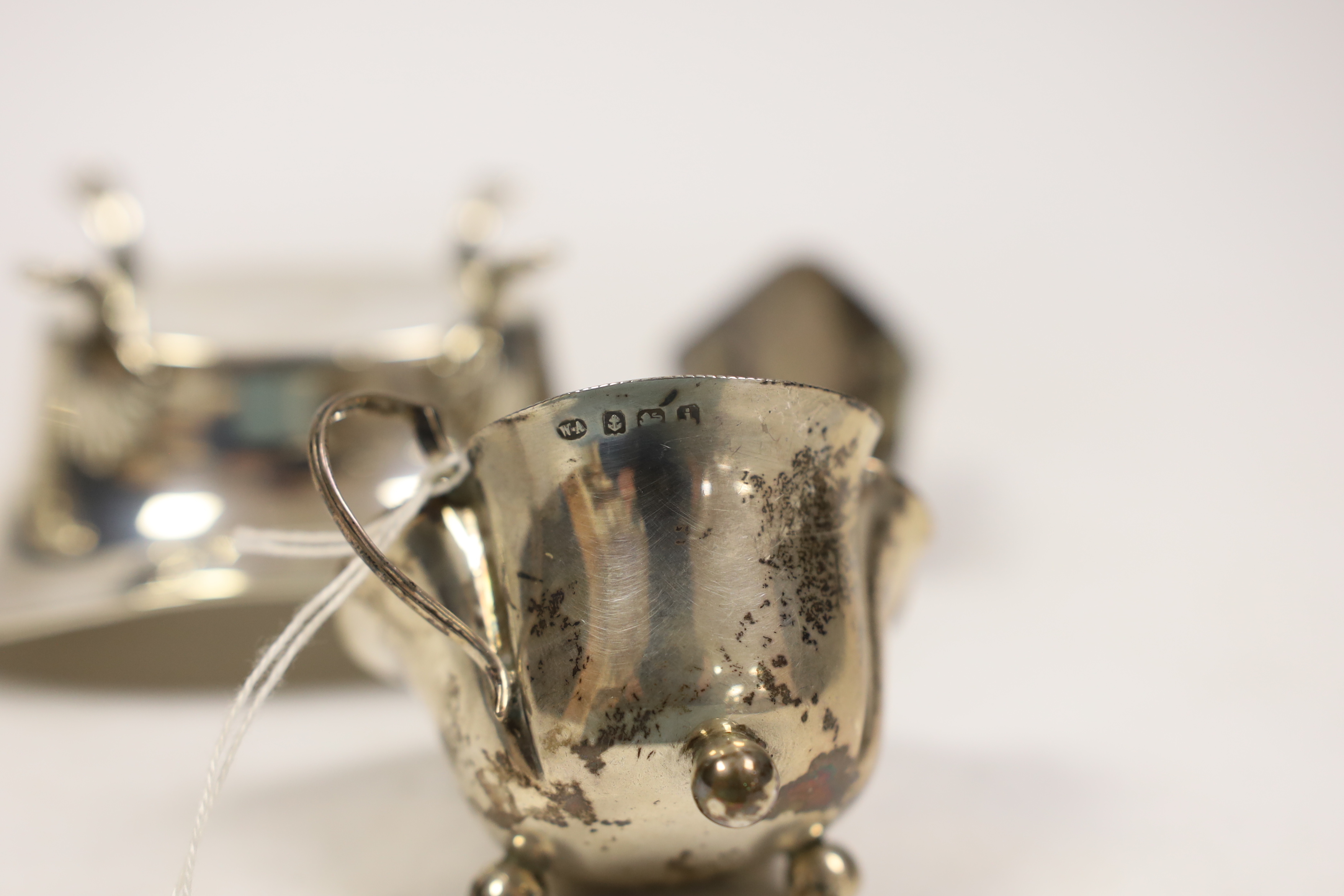 Small silverware, consisting:- a late Victorian helmet shaped cream jug, 1896; a George V oval sugar bowl, a late Victorian lighthouse sugar caster, 91mm, an Edwardian silver cream jug, 1908 and a silver tot.